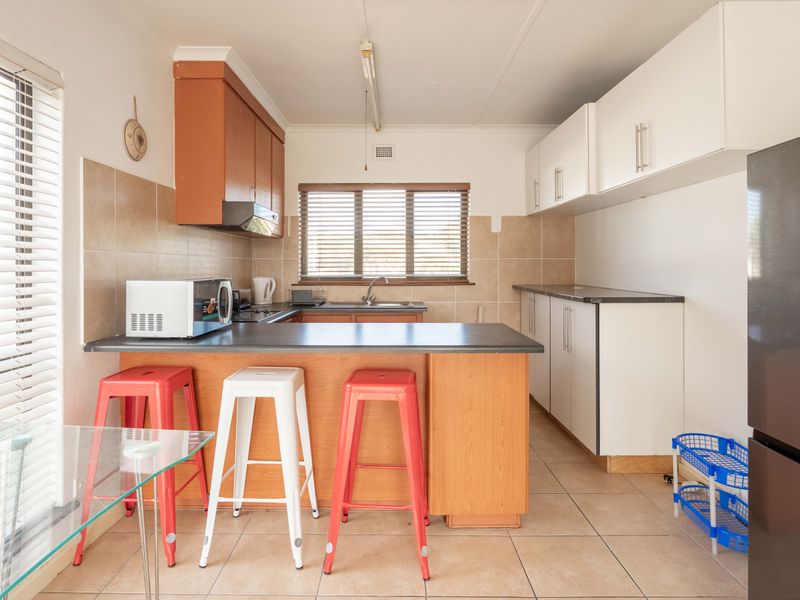 Functional kitchen featuring a breakfast bar, ample built-in cabinetry, tiled backsplash, and neutral floor tiles, offering a practical layout for daily use.