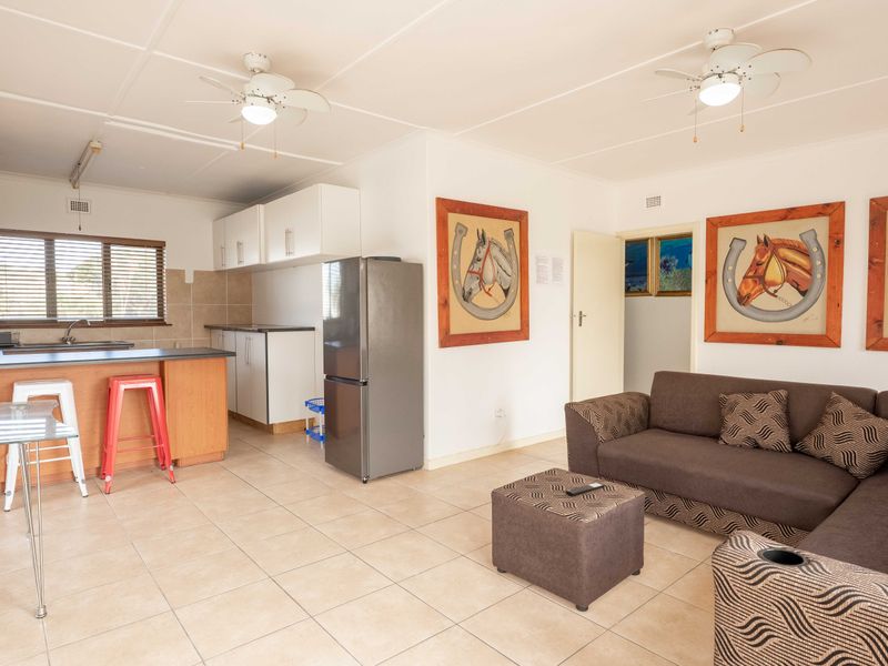 Open plan living area featuring a functional kitchen with cabinetry, tiled flooring, and dual ceiling fans, creating a combined kitchen and lounge space.
