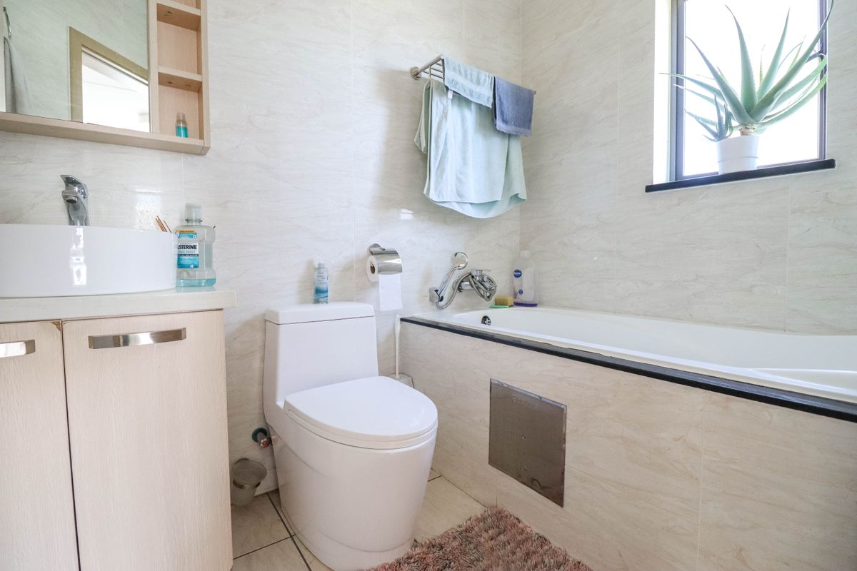 A functional bathroom featuring a built-in bathtub, a modern vessel sink vanity, and tiled walls with a window for natural light.