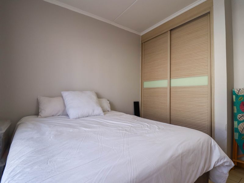 A bedroom featuring built-in sliding door wardrobes with a light wood finish and neutral wall tones.