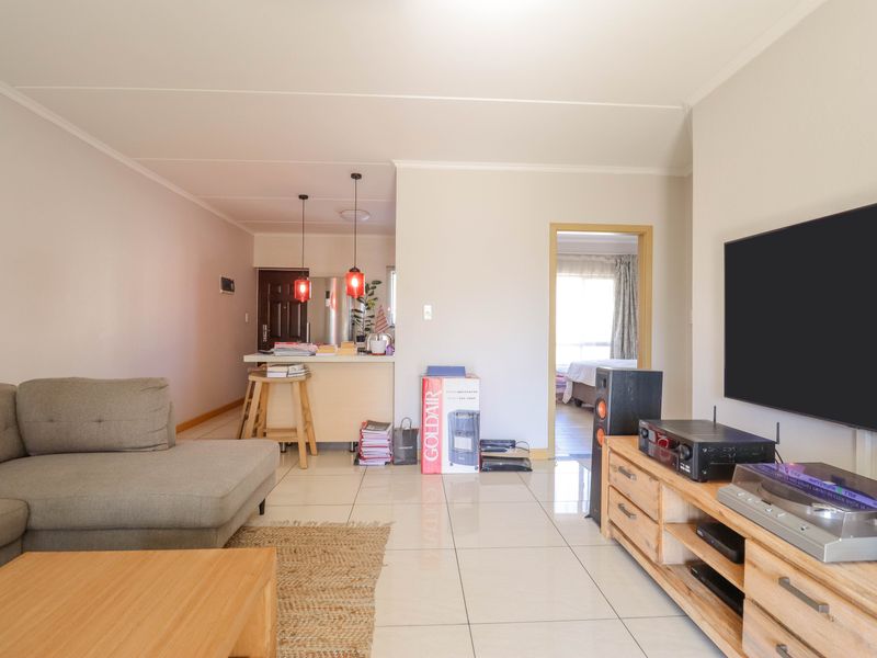 Open plan living area featuring tiled flooring, a breakfast counter, and direct access to an adjacent bedroom.