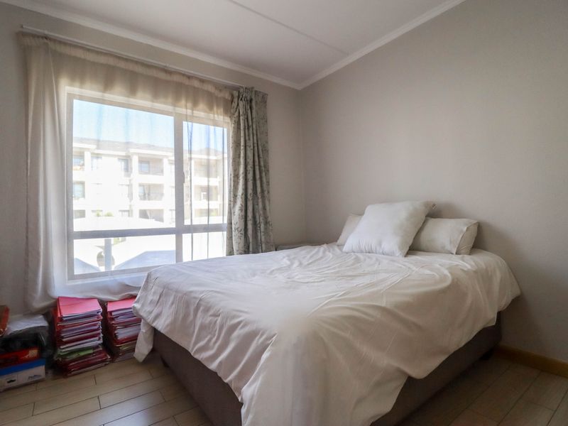 A bedroom featuring light-toned wood-look flooring and a large window allowing natural light, providing a neutral space ready for personalization.