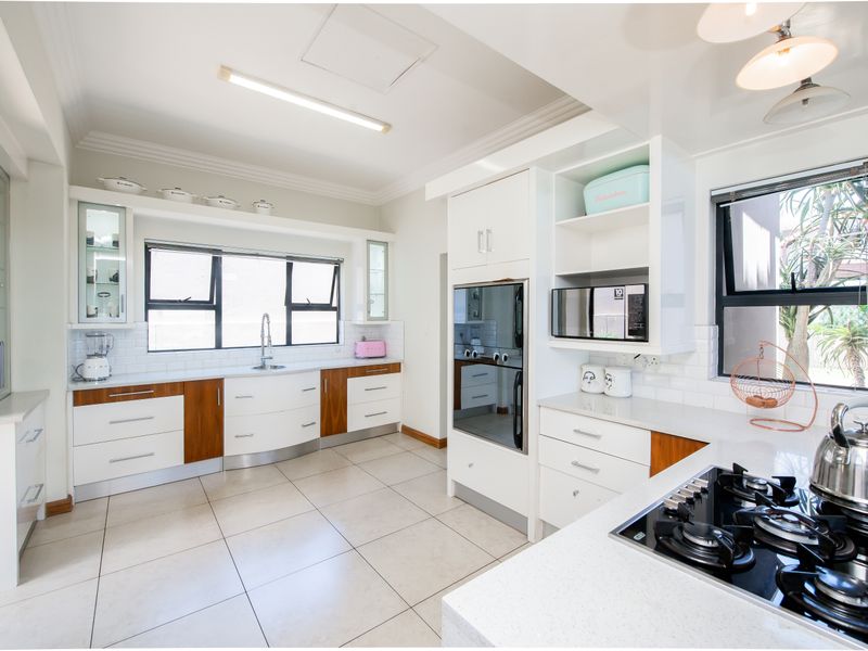 Modern kitchen featuring white and wood-tone cabinetry, quartz countertops, subway tile backsplash, built-in oven, and gas hob with ceramic floor tiles.