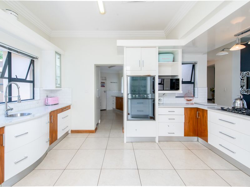 Modern kitchen featuring white and wood-toned cabinetry, stone countertops, built-in oven, gas hob, and a subway tile backsplash with tiled flooring.