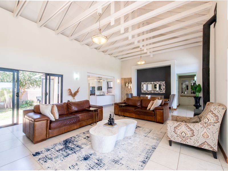 Spacious open-plan living area featuring high exposed beam ceilings, a modern fireplace, and large sliding doors leading to the outdoor space.