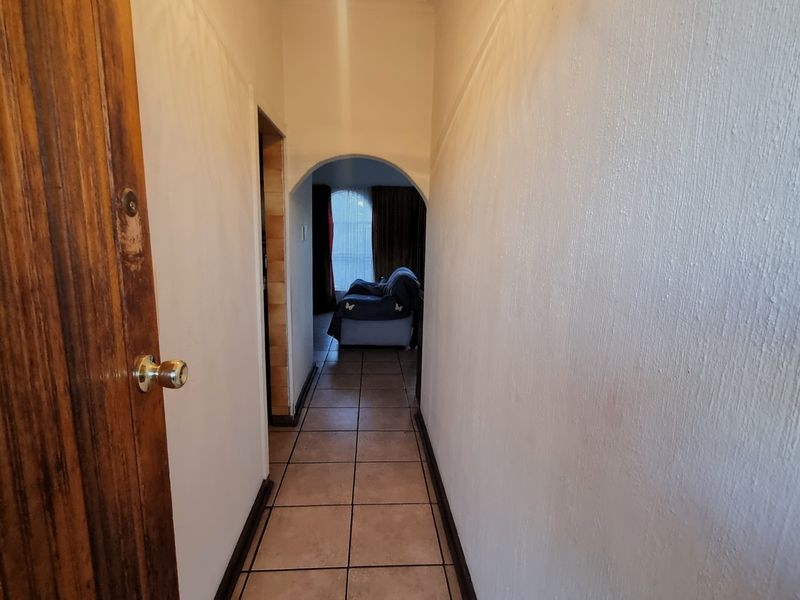 A functional hallway featuring tiled flooring and an arched entryway leading into the living area.