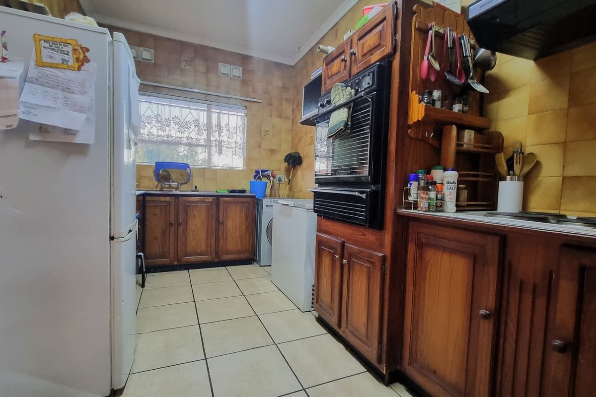 A functional kitchen featuring traditional wooden cabinetry, tiled backsplash, and built-in oven, offering a dated aesthetic with potential for modern renovation.
