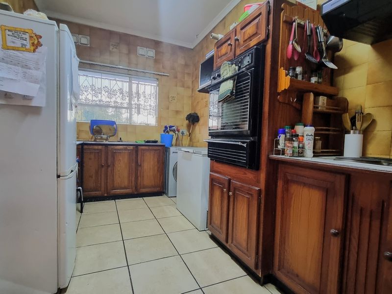 A functional kitchen featuring traditional wooden cabinetry, tiled backsplash, and built-in oven, offering a dated aesthetic with potential for modern renovation.