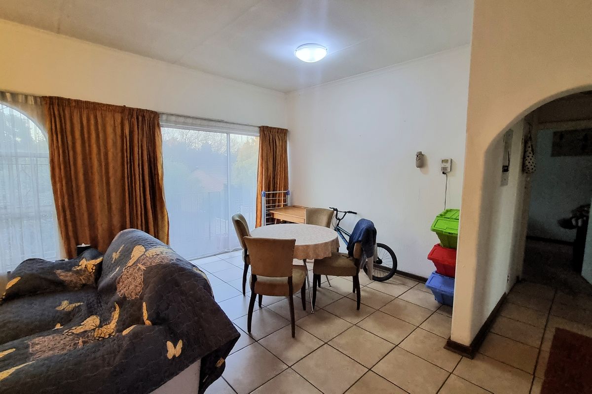 A living area featuring tiled flooring, an arched entryway, and a sliding glass door providing access to the exterior.
