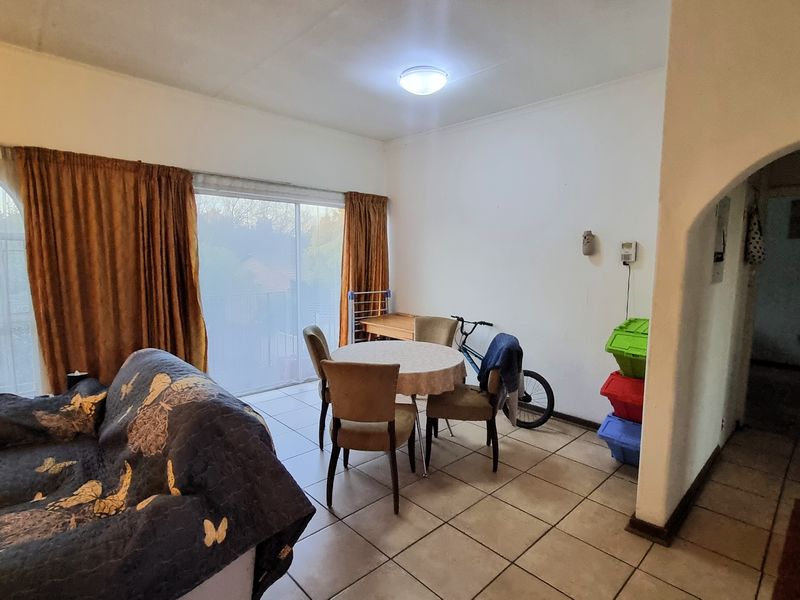 A living area featuring tiled flooring, an arched entryway, and a sliding glass door providing access to the exterior.