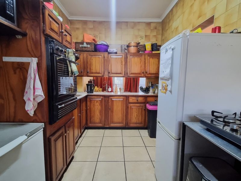 A functional kitchen featuring traditional wooden cabinetry, tiled backsplash, and built-in cooking appliances, offering a classic layout with potential for modern updates.