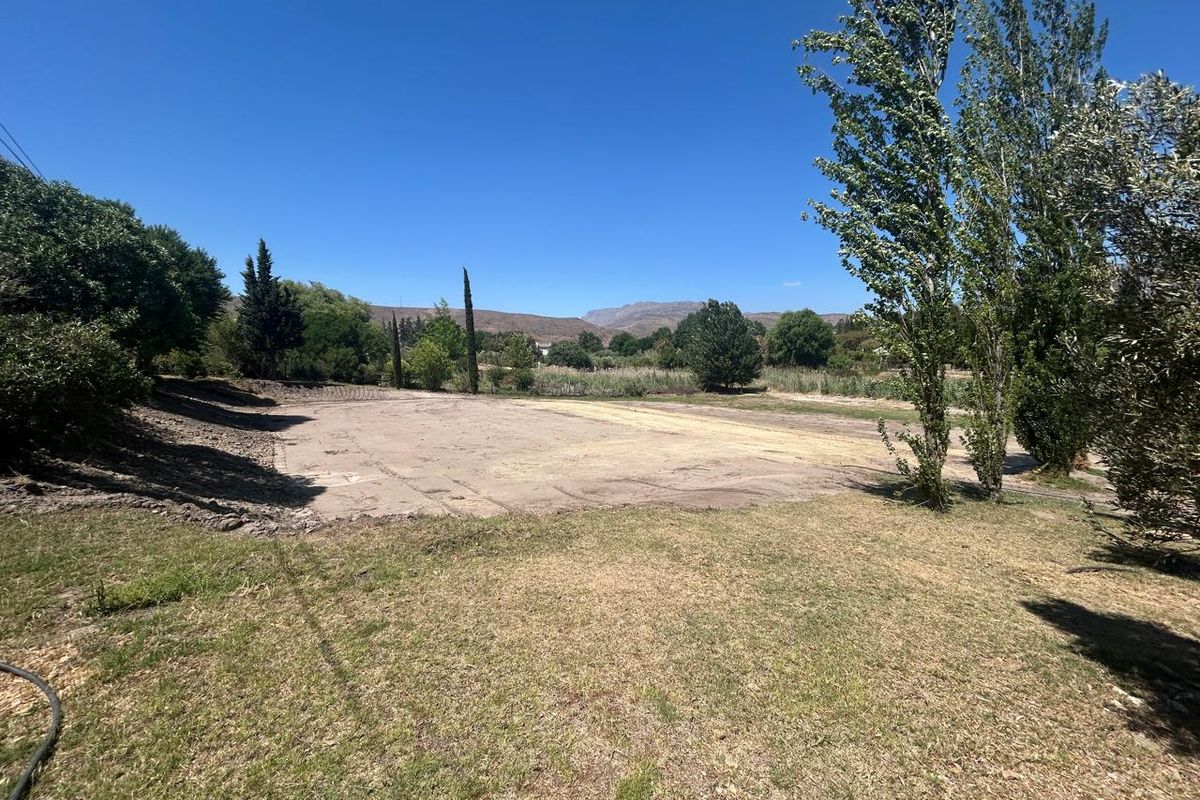 A spacious, level plot of vacant residential land featuring established trees and scenic mountain views, offering a blank canvas for development.