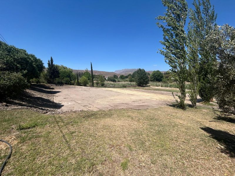 A spacious, level plot of vacant residential land featuring established trees and scenic mountain views, offering a blank canvas for development.