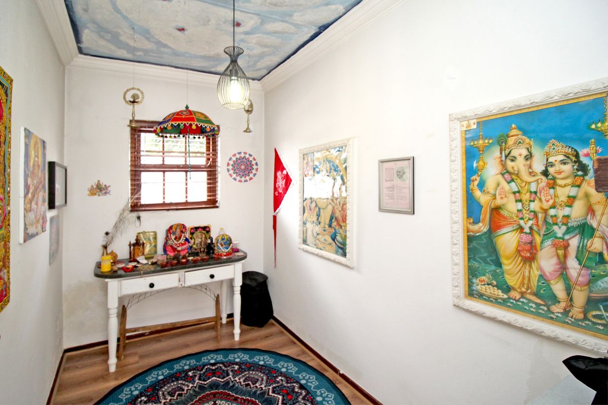 A small room featuring wood-look flooring, a painted cloud-effect ceiling, and a window with wooden blinds.