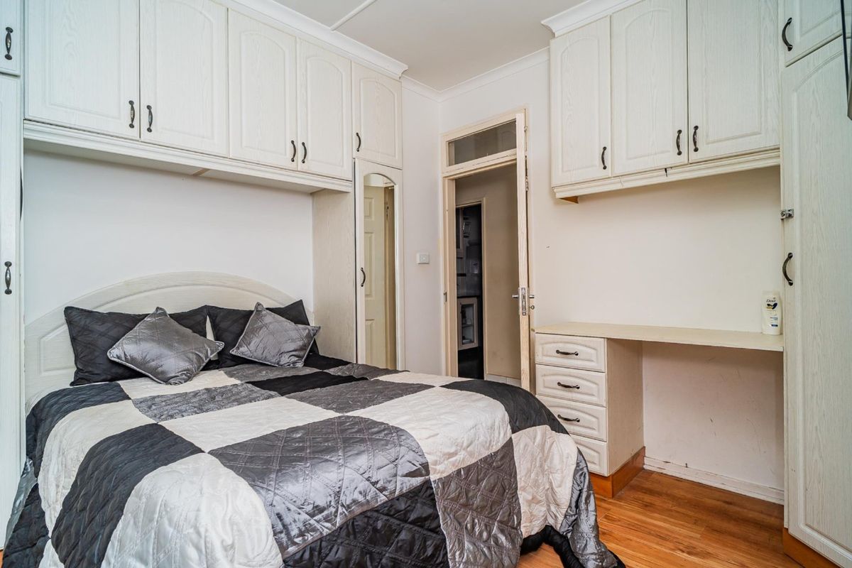 Bedroom featuring extensive built-in cabinetry, integrated desk space, and timber flooring, offering functional storage and a practical layout.