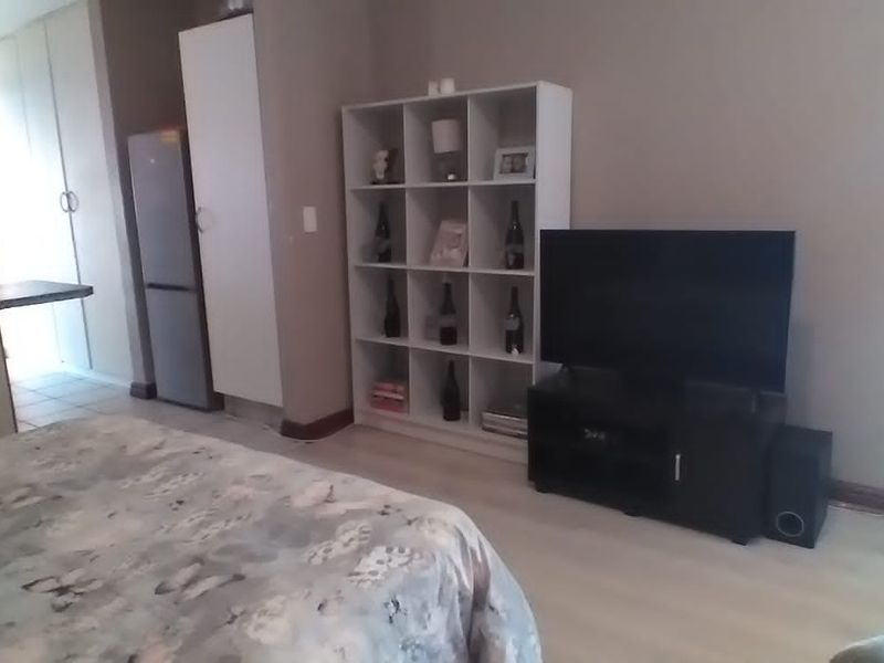 A bedroom featuring built-in cupboards and a window with security bars, offering a functional living space.