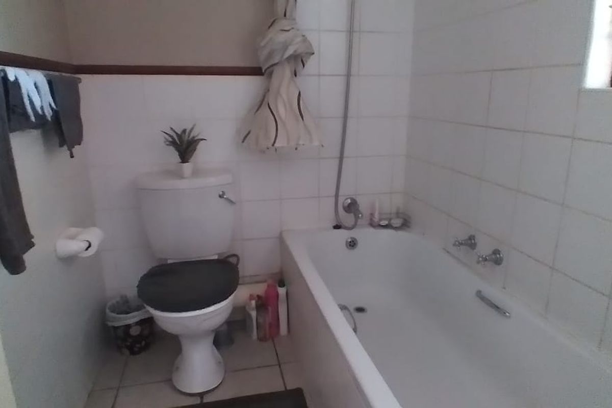 A functional bathroom featuring a standard bathtub, toilet, and tiled wall finishes, presenting an opportunity for cosmetic updates.