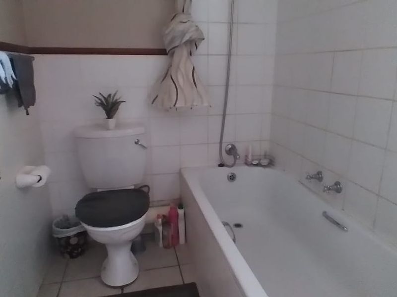 A functional bathroom featuring a standard bathtub, toilet, and tiled wall finishes, presenting an opportunity for cosmetic updates.