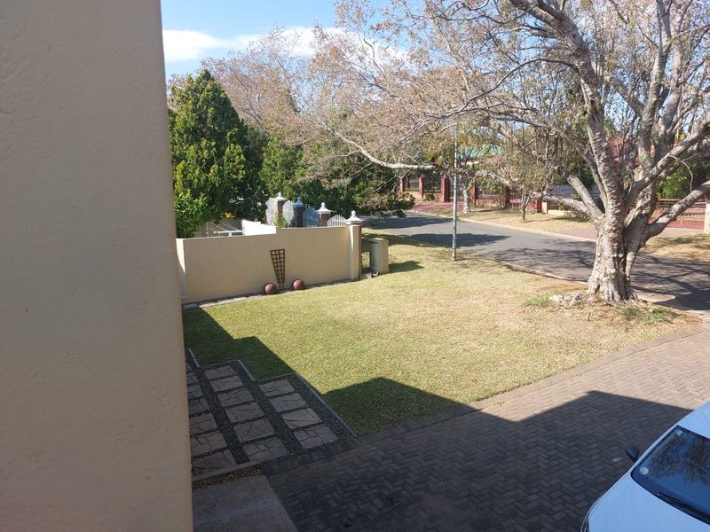 An elevated view of the front garden, featuring a paved driveway, manicured lawn, and perimeter boundary wall.