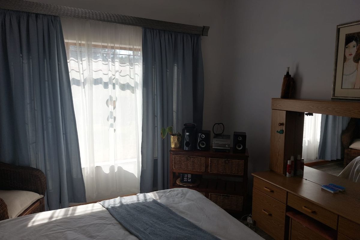 A bedroom featuring natural light through window curtains, providing a comfortable and functional living space.