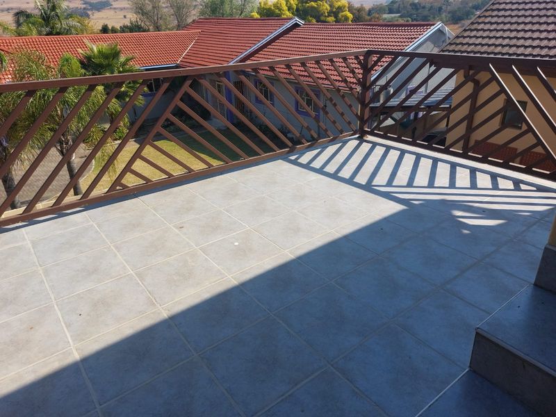 An elevated balcony featuring tiled flooring and a metal balustrade, offering views over the surrounding residential area.