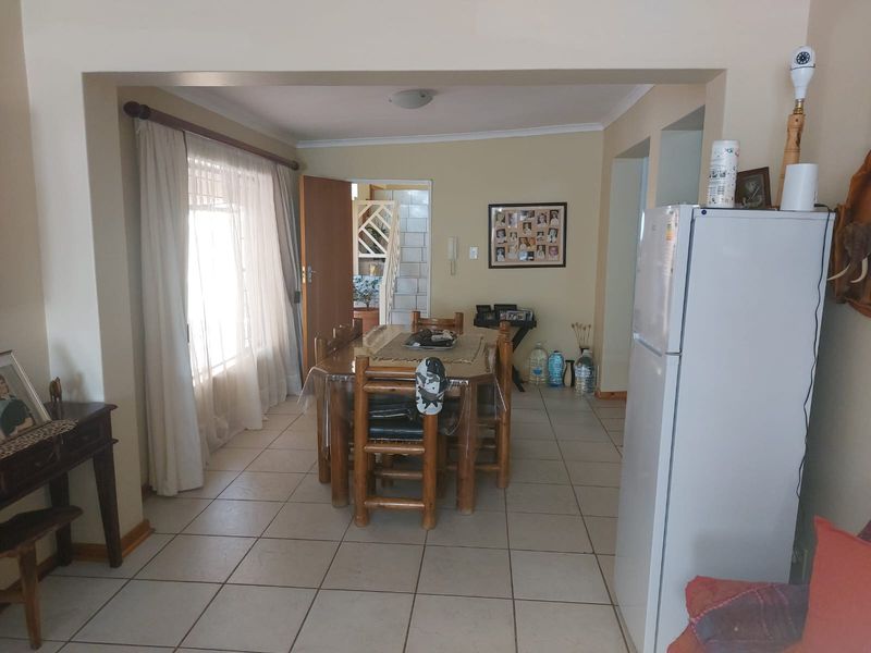 Open plan dining area featuring tiled flooring and large windows, providing a functional space with direct access to the hallway and staircase.