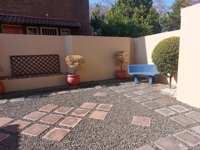 A private courtyard garden featuring paved pathways, gravel landscaping, and high perimeter walls, providing a low-maintenance outdoor space.