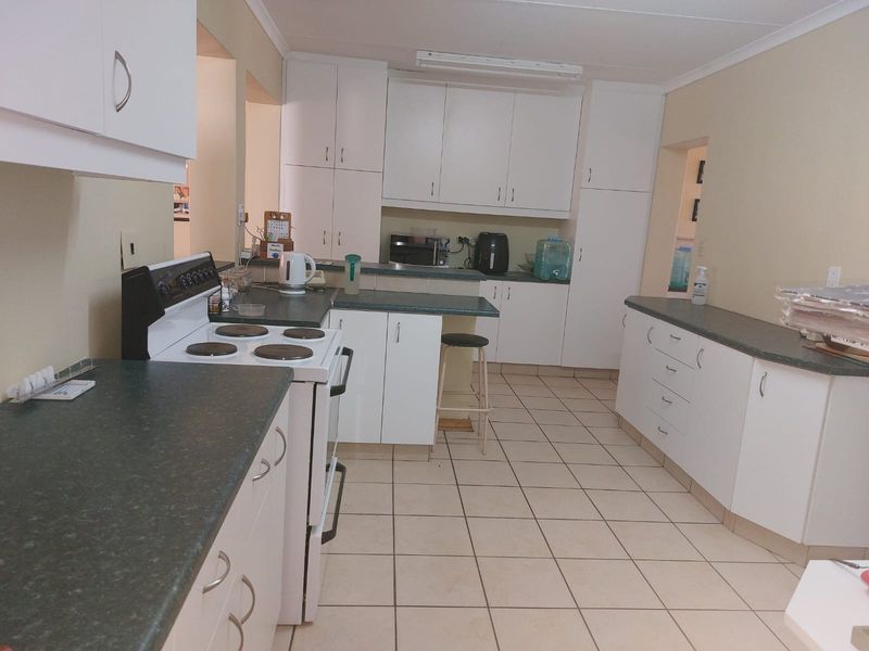 Functional kitchen featuring white cabinetry, dark laminate countertops, tiled flooring, and a freestanding electric stove.