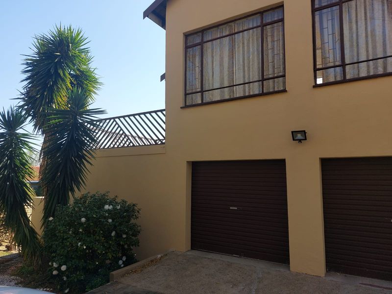 Exterior view of the property featuring a double garage with roller doors, upper-level windows, and a balcony with metal railings.
