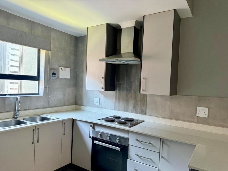 Modern kitchen featuring neutral cabinetry, stone countertops, a built-in oven, electric hob, and stainless steel extractor fan with tiled backsplash.