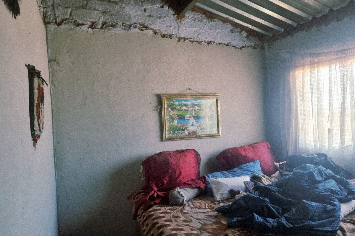 A bedroom featuring exposed brickwork and a corrugated metal roof, requiring significant renovation to improve the wall finishes and overall structural presentation.
