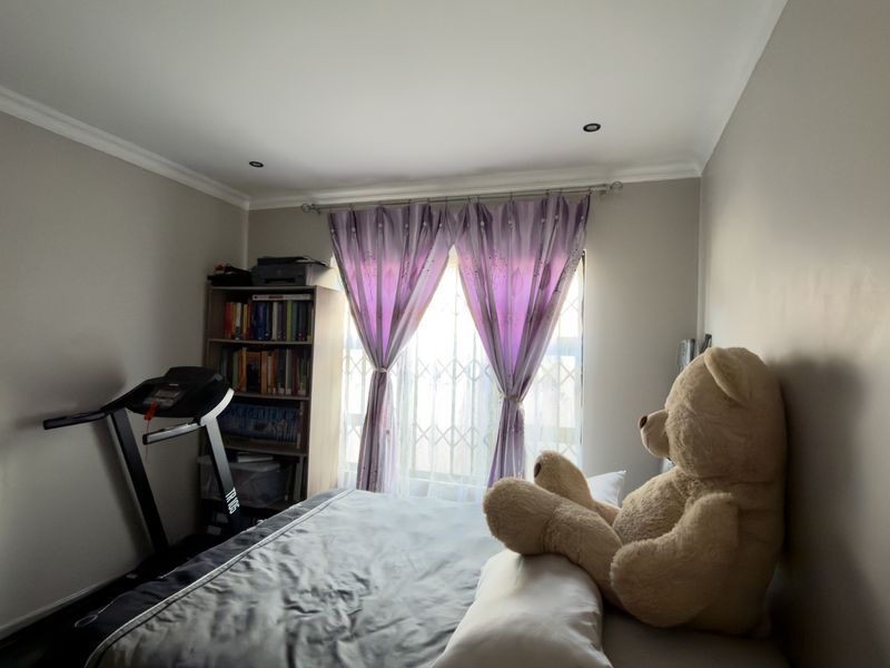 A bedroom featuring neutral wall tones, recessed downlighting, and a window fitted with a security gate.