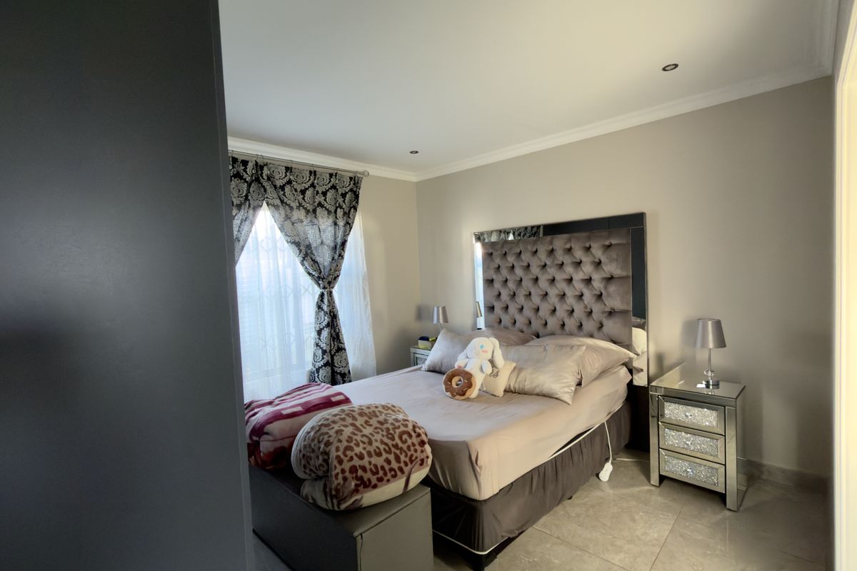 A well-maintained bedroom featuring tiled flooring, recessed downlighting, and coved cornicing, offering a clean and comfortable living space.