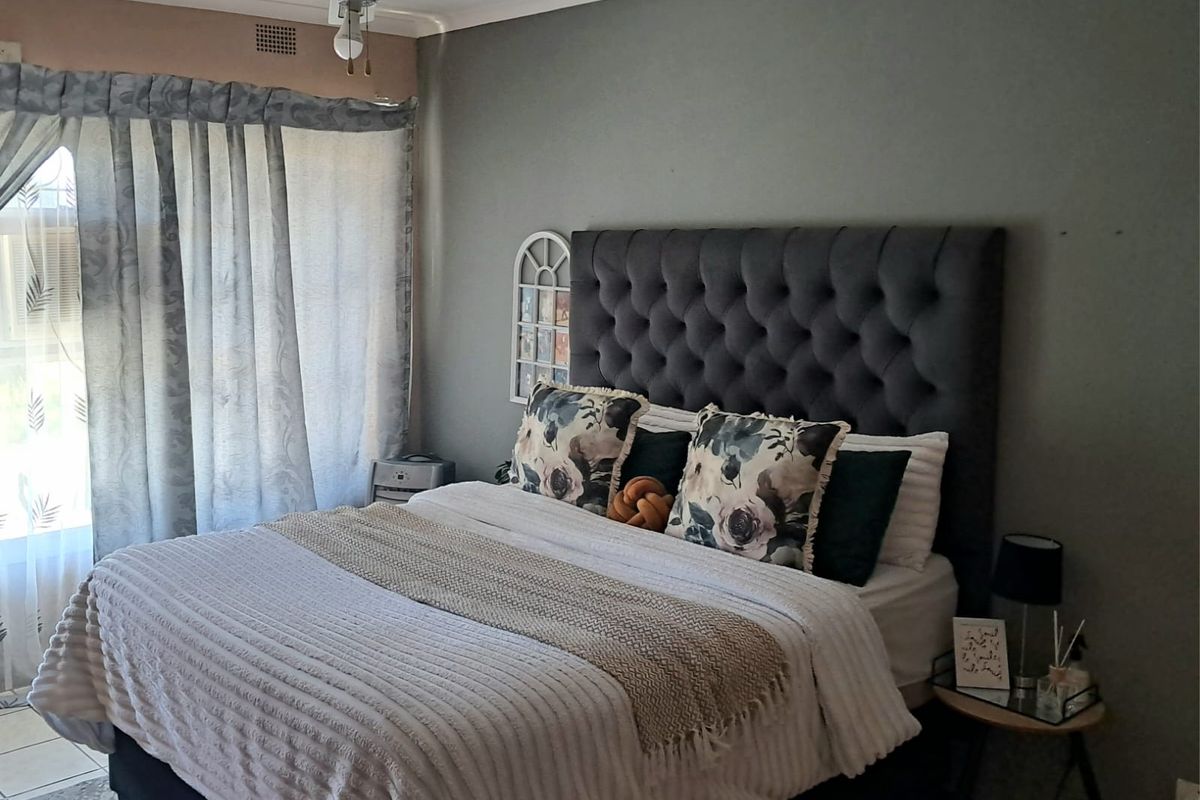 A comfortable bedroom featuring tiled flooring and a ceiling fan, with neutral wall tones and natural light from the window.