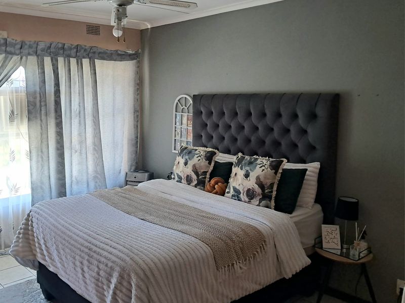 A comfortable bedroom featuring tiled flooring and a ceiling fan, with neutral wall tones and natural light from the window.