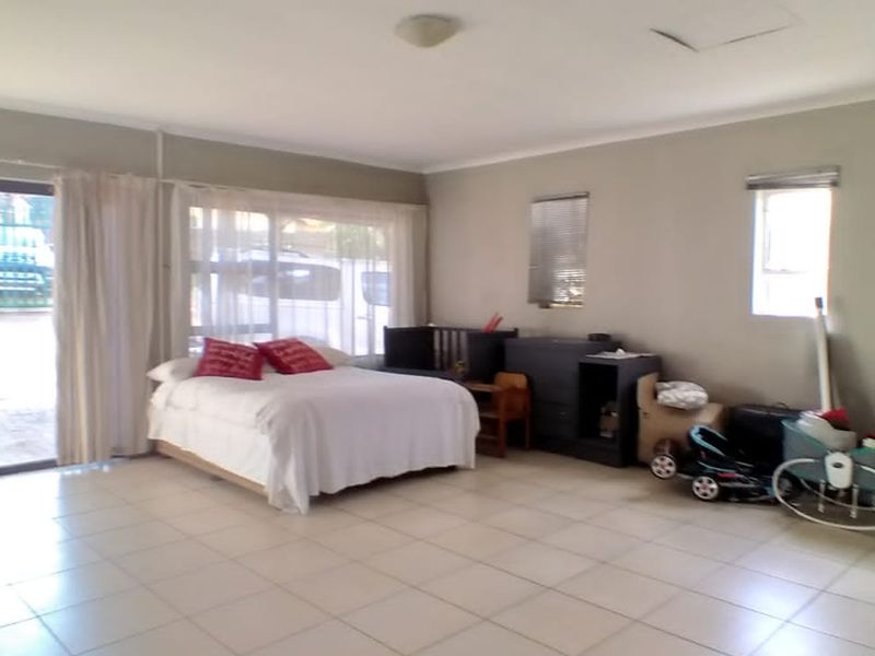 Spacious bedroom featuring tiled flooring and a large sliding glass door providing direct access to the exterior.