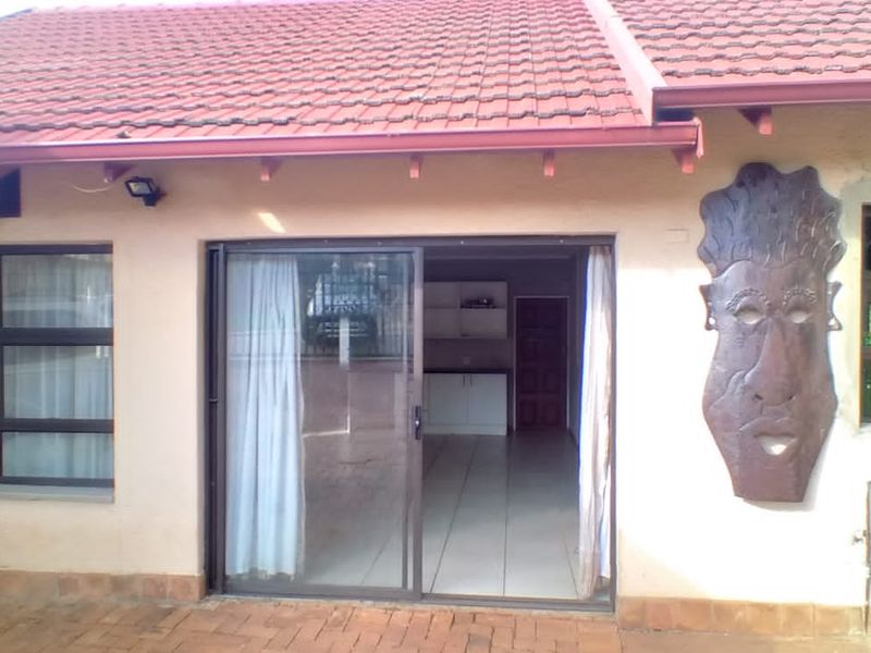 Rear exterior view of the cottage featuring a tiled roof, sliding glass doors, and brick paved patio area.