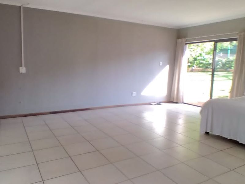 Open-plan living area featuring tiled flooring, kitchen cabinetry, and a sliding glass door providing direct access to the garden.