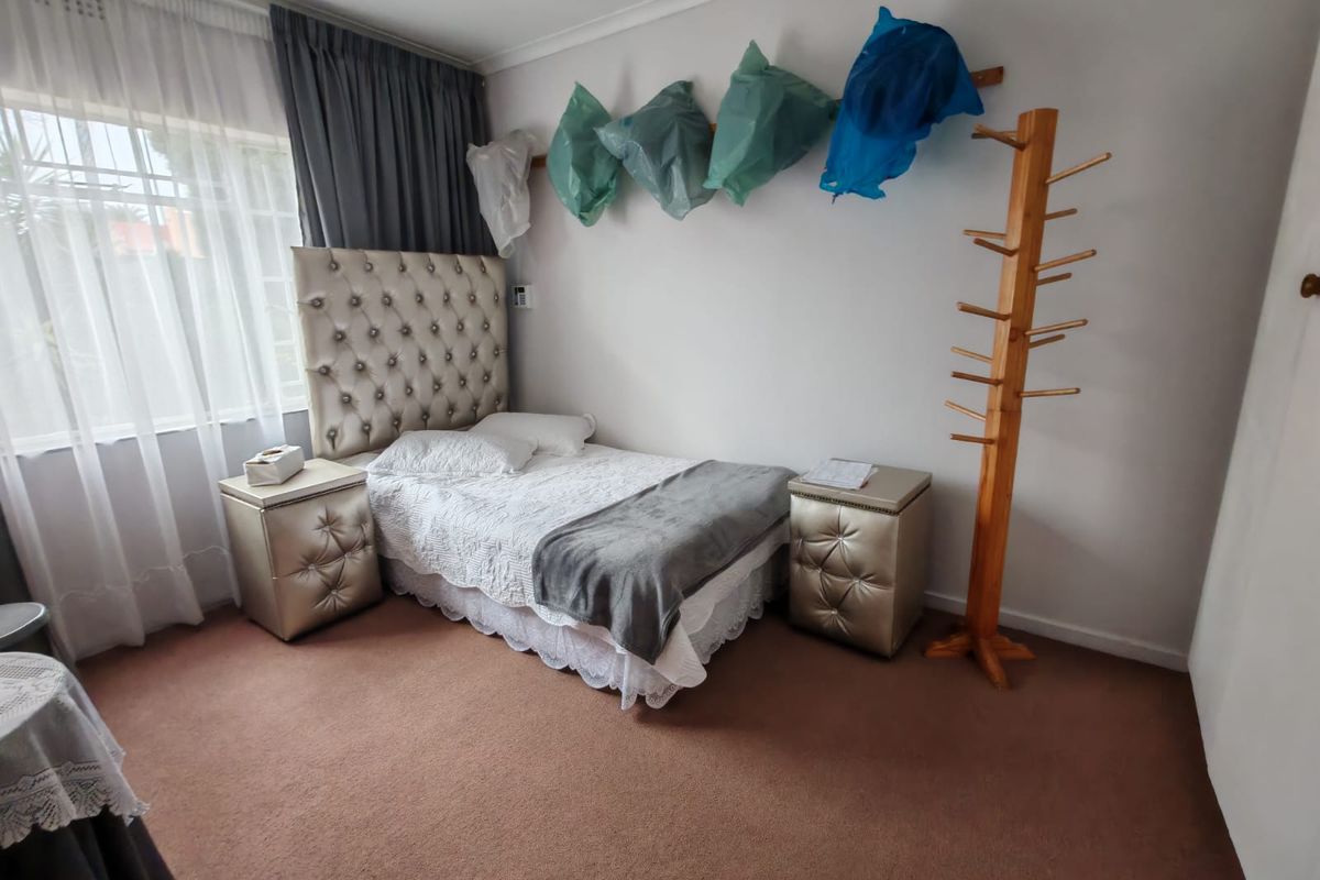A bedroom featuring carpeted flooring, a large window with curtains, and neutral wall finishes.