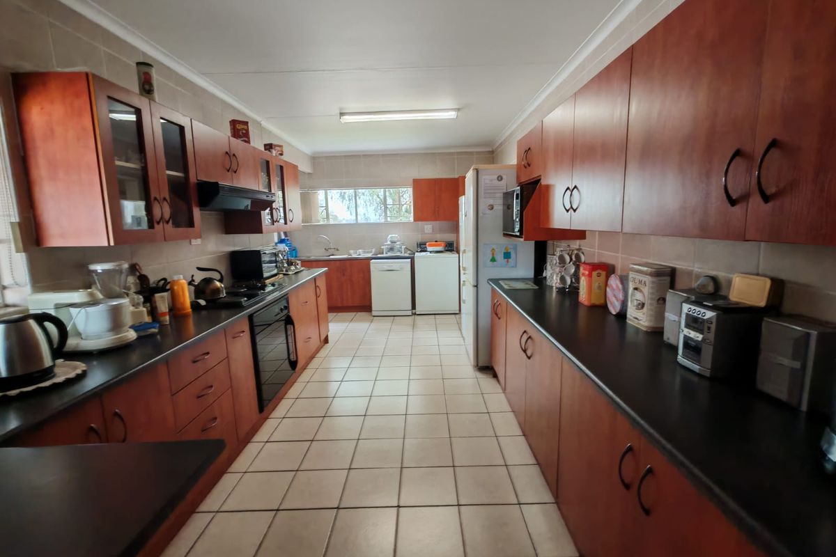 A functional galley-style kitchen featuring extensive wooden cabinetry, dark countertops, tiled flooring, and integrated appliance spaces.