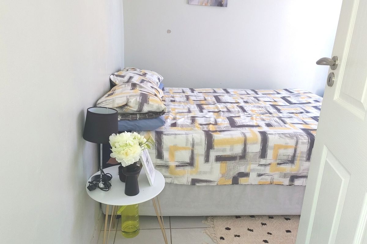 A compact bedroom featuring tiled flooring and neutral wall finishes, suitable for a guest room or home office setup.