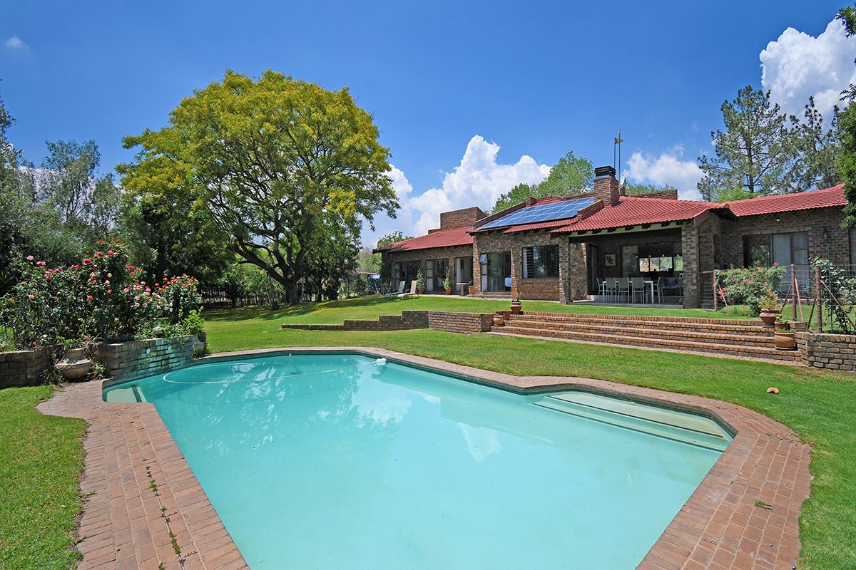 Spacious rear garden featuring a swimming pool, brick patio area, and a brick-faced house with solar panels on the roof.