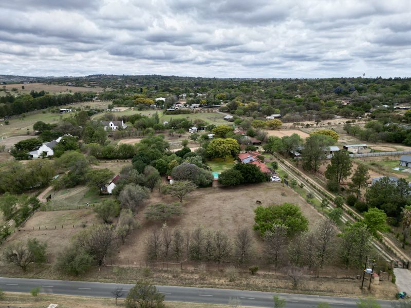 An aerial view of a large residential property featuring expansive grounds, mature trees, a swimming pool, and established fencing in a semi-rural setting.
