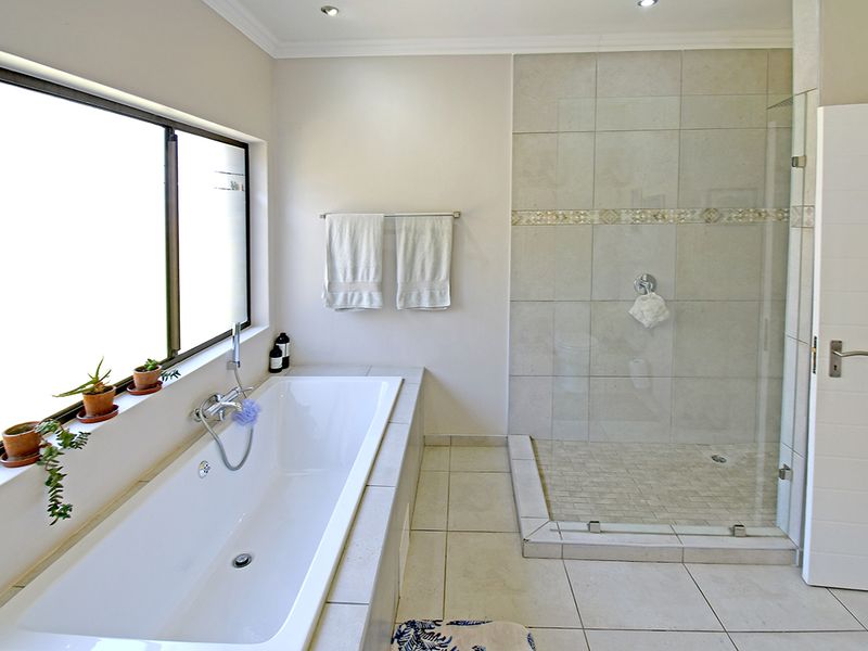 Modern bathroom featuring a built-in bathtub, a spacious walk-in shower with glass enclosure, and neutral floor-to-ceiling tiling.