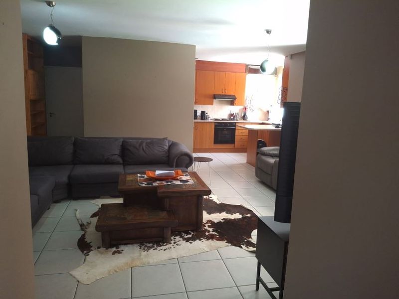 Open-plan living area featuring tiled floors and a functional kitchen with built-in cabinetry, oven, and hob.