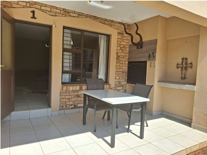 A covered patio area featuring a built-in braai, tiled flooring, and direct access to the interior living space.