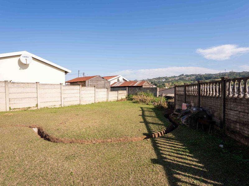 A rear garden area featuring a lawn, precast concrete boundary walls, and a decorative balustrade wall section.