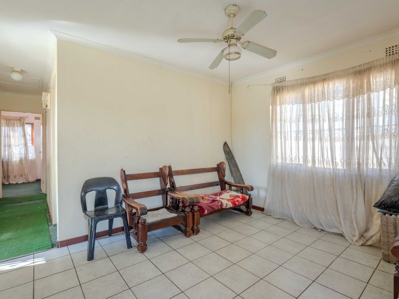 A living room featuring ceramic floor tiles, a ceiling fan, and neutral wall finishes, offering a blank canvas for potential renovation and modernization.