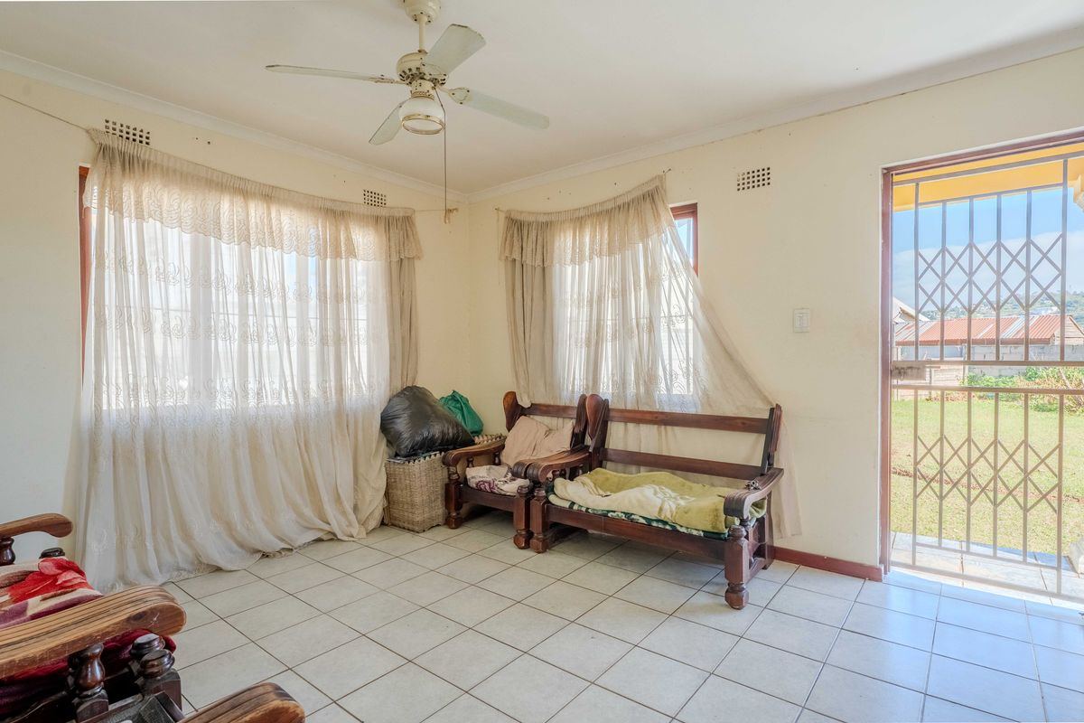 A living room featuring tiled flooring, a ceiling fan, and direct access to the exterior through a security gate.