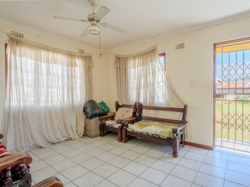 A living room featuring tiled flooring, a ceiling fan, and direct access to the exterior through a security gate.